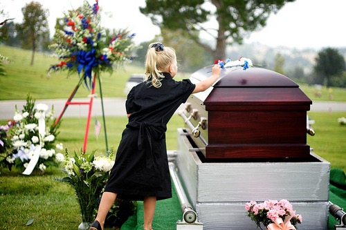 child laying flowers on coffin