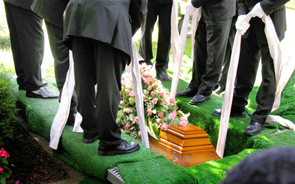 Pall bearers lowering coffin into grave